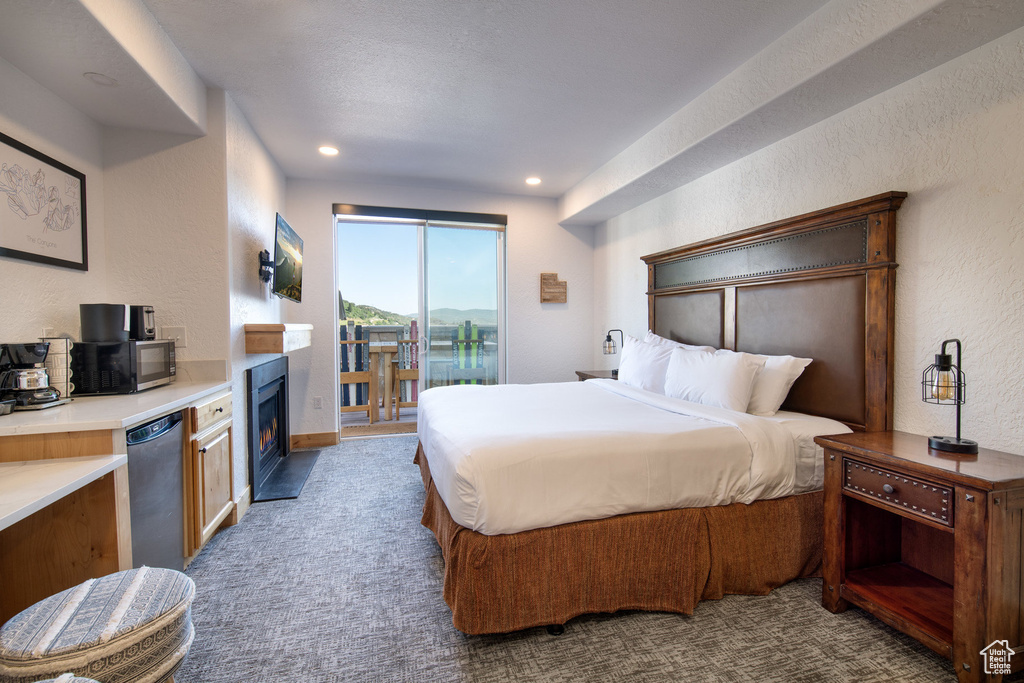 Bedroom featuring access to exterior, a textured wall, carpet flooring, a fireplace with flush hearth, and recessed lighting