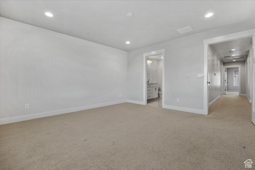 Unfurnished bedroom featuring connected bathroom, recessed lighting, light colored carpet, and baseboards