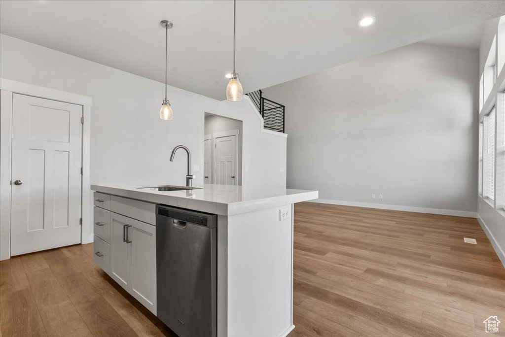 Kitchen featuring light wood-style floors, light countertops, dishwasher, a sink, and pendant lighting
