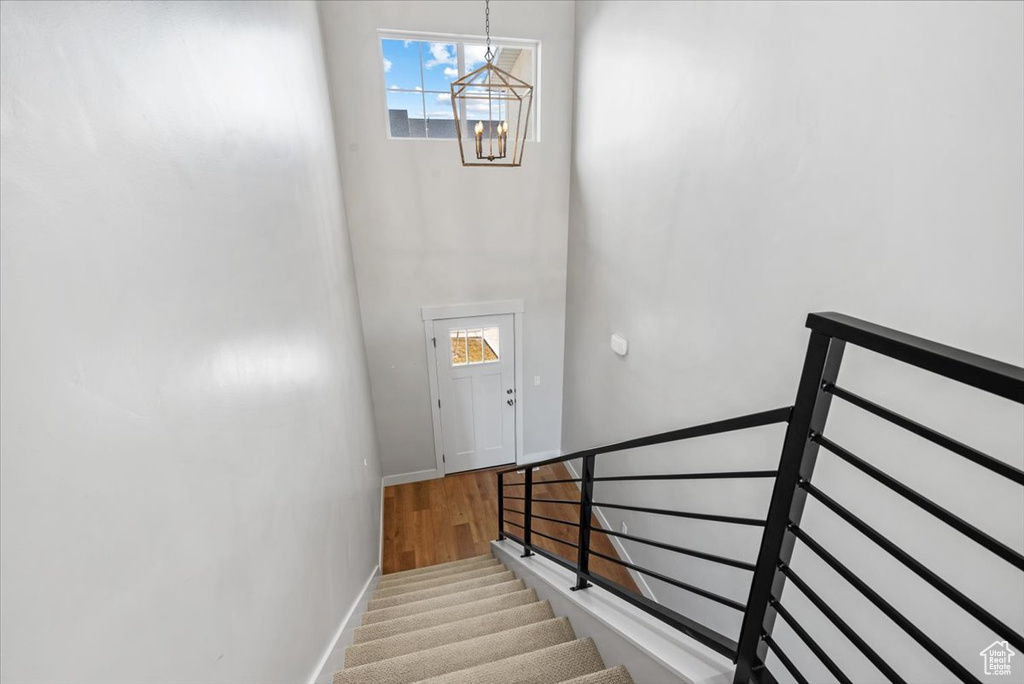 Staircase featuring wood finished floors, plenty of natural light, a chandelier, and baseboards
