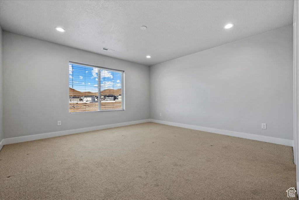 Empty room featuring recessed lighting, visible vents, light colored carpet, and baseboards