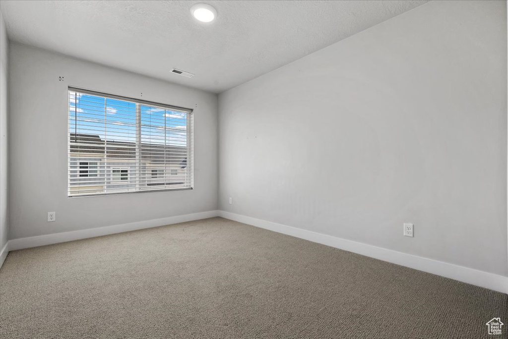 Carpeted empty room with visible vents and baseboards