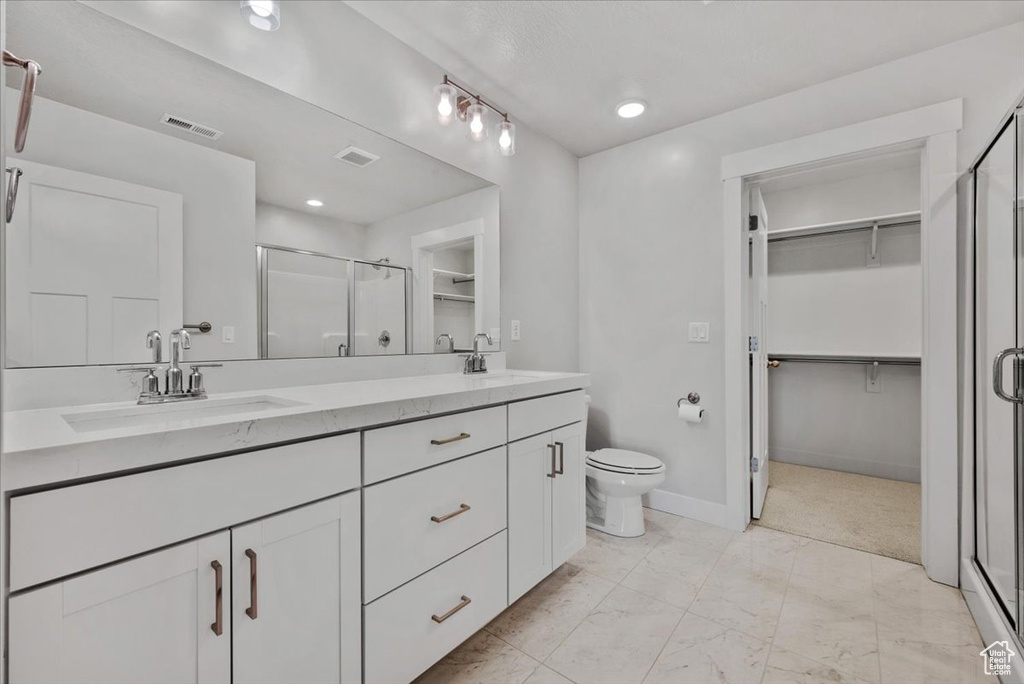 Bathroom featuring a shower stall, double vanity, marble finish floor, and a sink