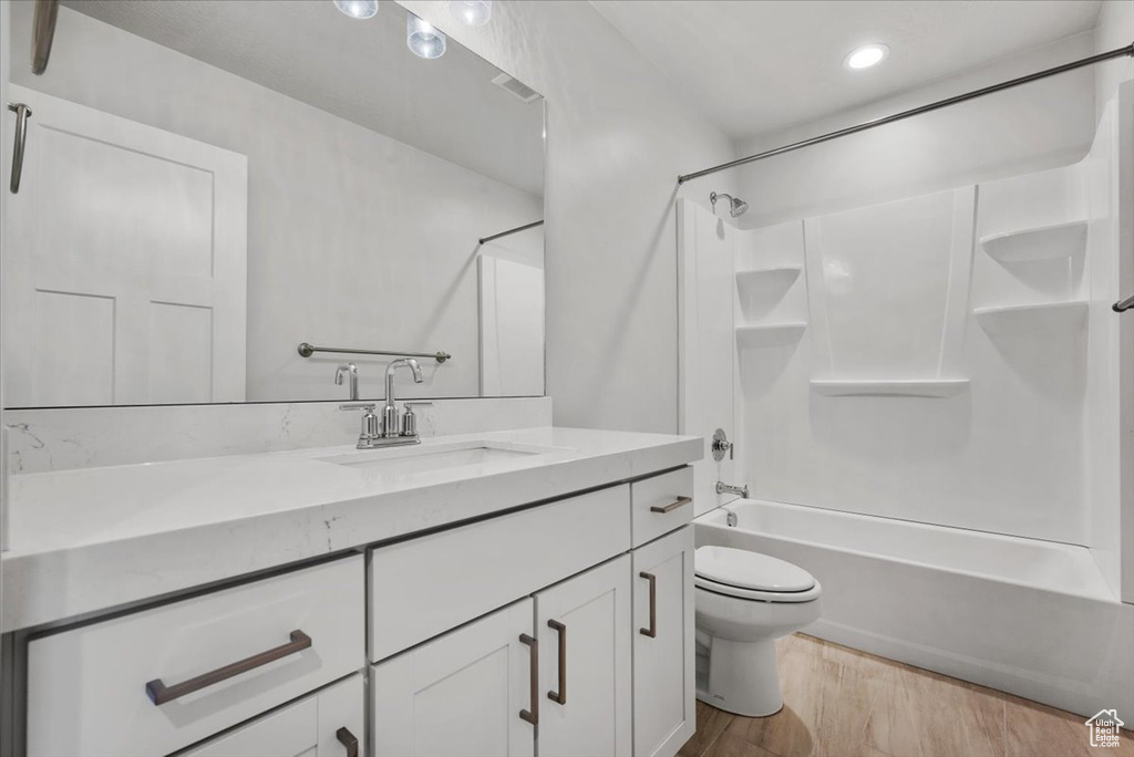 Full bathroom with recessed lighting, vanity, shower / bath combination, toilet, and wood finished floors