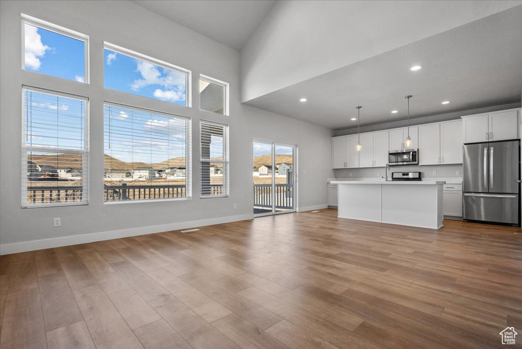 Unfurnished living room with recessed lighting, wood finished floors, and baseboards