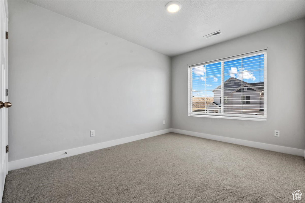 Unfurnished room featuring visible vents, baseboards, and carpet floors