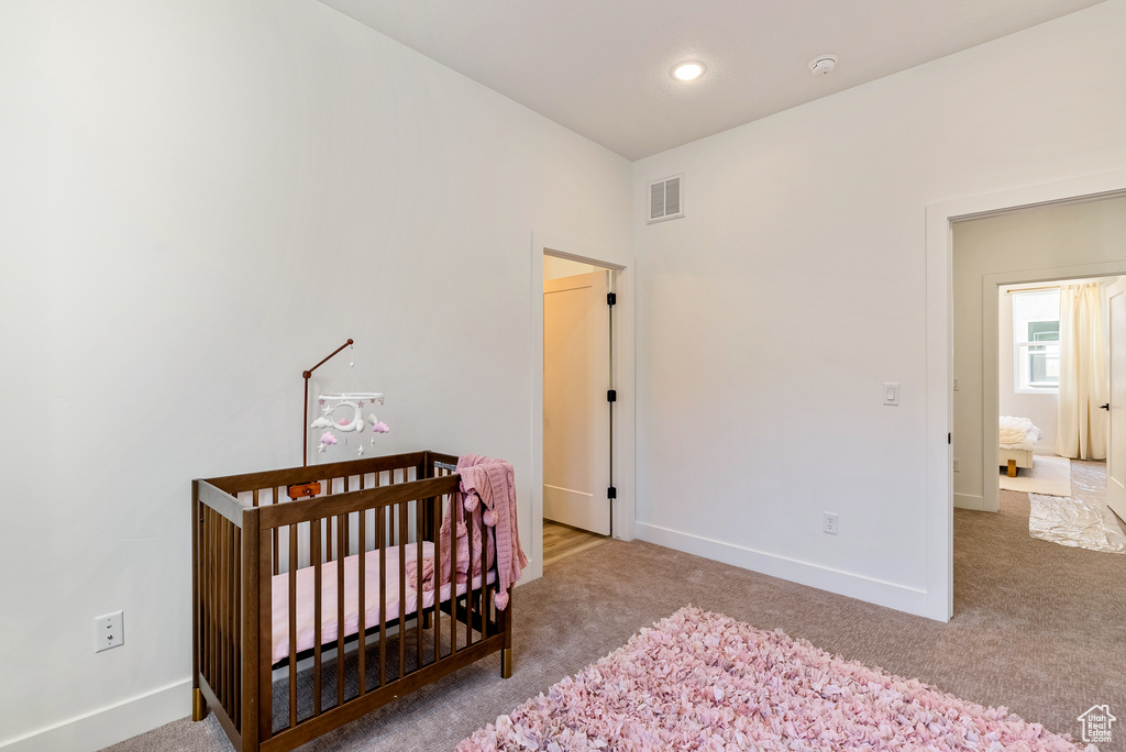 Bedroom featuring a crib and carpet floors