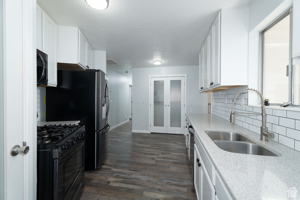 Kitchen with tasteful backsplash, sink, black appliances, dark hardwood / wood-style floors, and white cabinetry