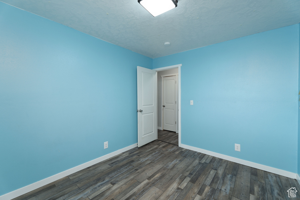 Empty room featuring dark hardwood / wood-style floors and a textured ceiling