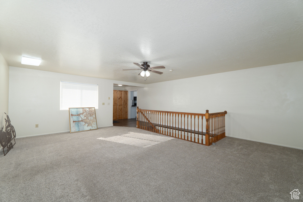 Spare room featuring a textured ceiling, carpet floors, and ceiling fan