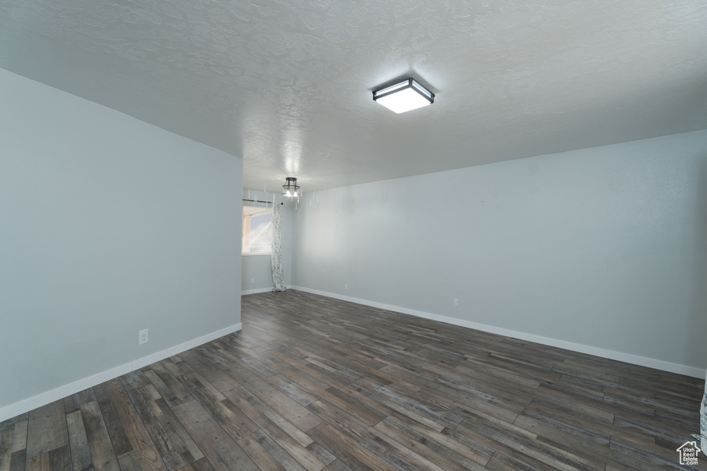 Empty room featuring a textured ceiling and dark hardwood / wood-style floors