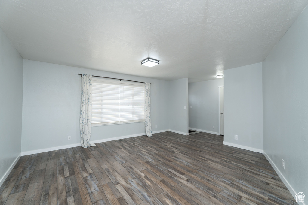 Empty room featuring dark hardwood / wood-style flooring and a textured ceiling