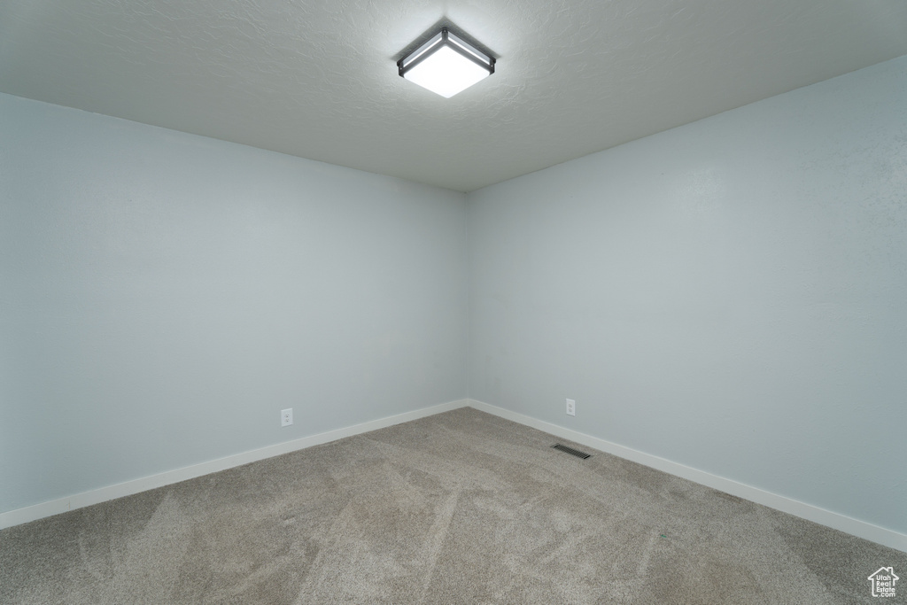 Carpeted empty room featuring a textured ceiling