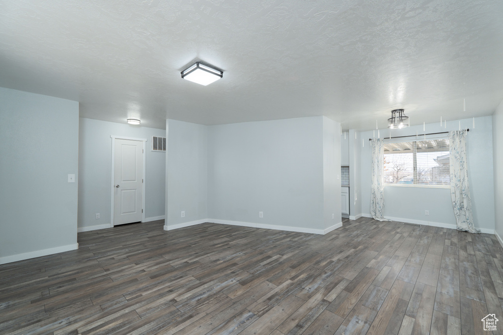 Unfurnished room with a textured ceiling and dark wood-type flooring