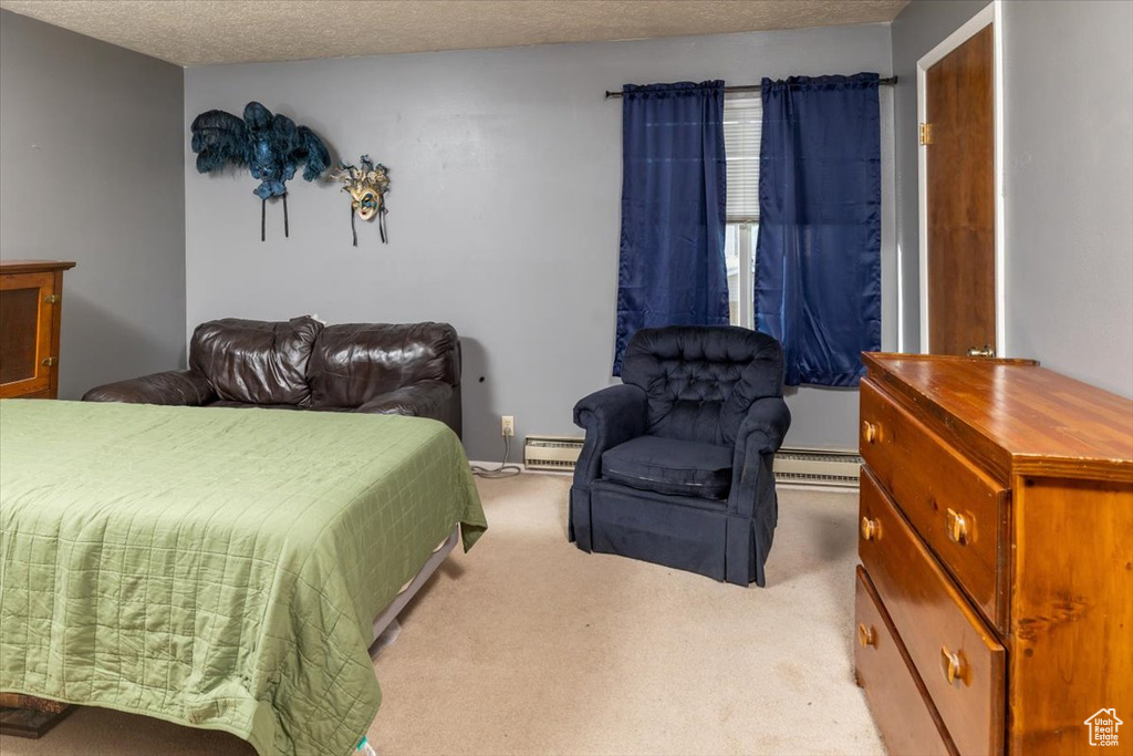 Carpeted bedroom with a textured ceiling and a baseboard radiator