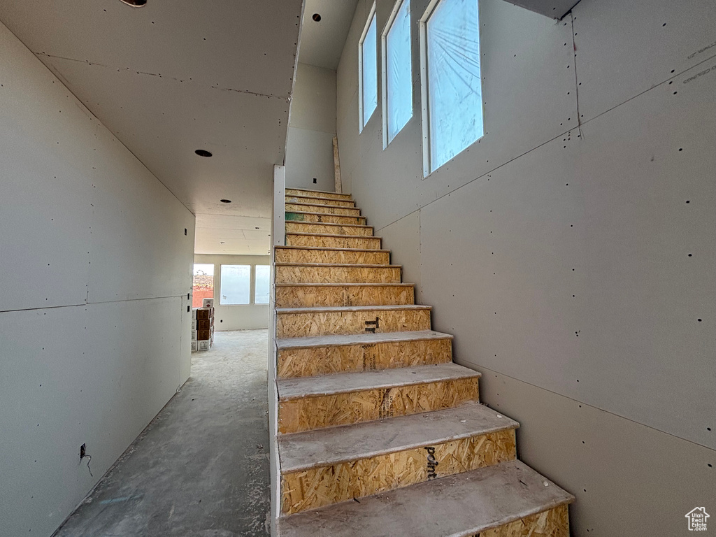 Staircase featuring unfinished concrete floors