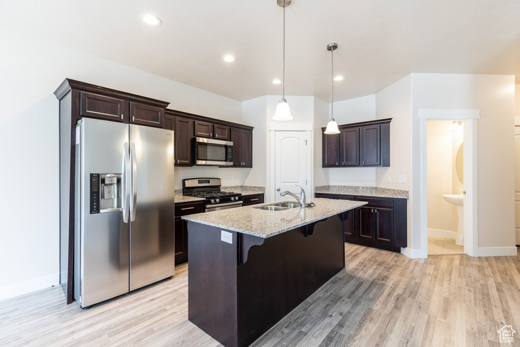 Kitchen with a kitchen island with sink, sink, a breakfast bar area, light hardwood / wood-style floors, and stainless steel appliances