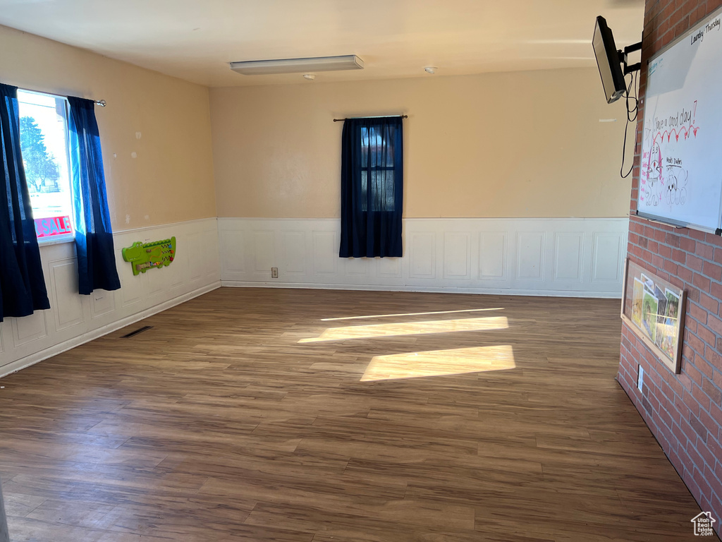 Empty room with dark hardwood / wood-style floors and brick wall