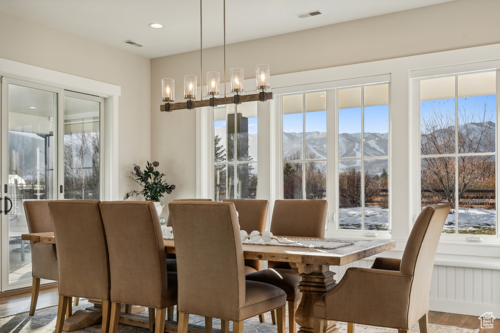 Dining area featuring a chandelier, a mountain view, a healthy amount of sunlight, and hardwood / wood-style flooring