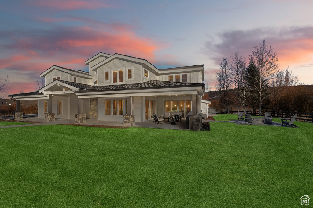 Back house at dusk with french doors, a yard, a patio area, and exterior kitchen