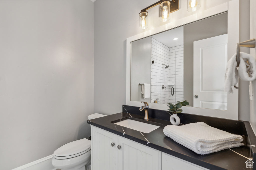 Bathroom with toilet, vanity, and walk in shower