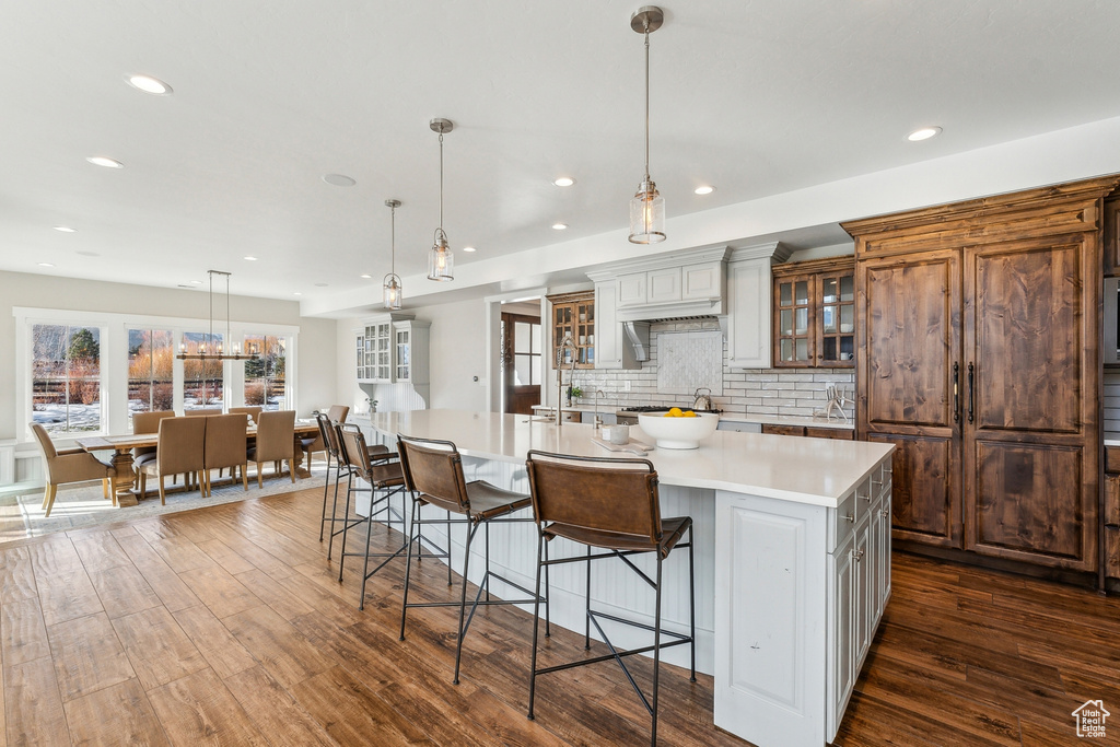 Kitchen featuring dark hardwood / wood-style floors, white cabinetry, hanging light fixtures, and a spacious island