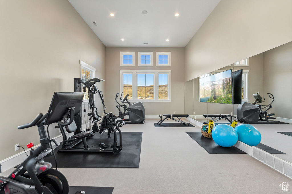 Workout room with carpet flooring and a towering ceiling