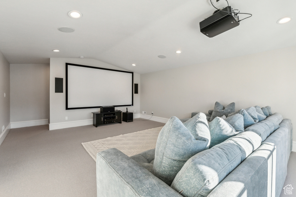 Carpeted home theater room with vaulted ceiling