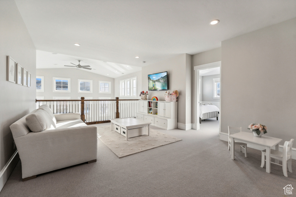 Carpeted living room featuring ceiling fan and lofted ceiling