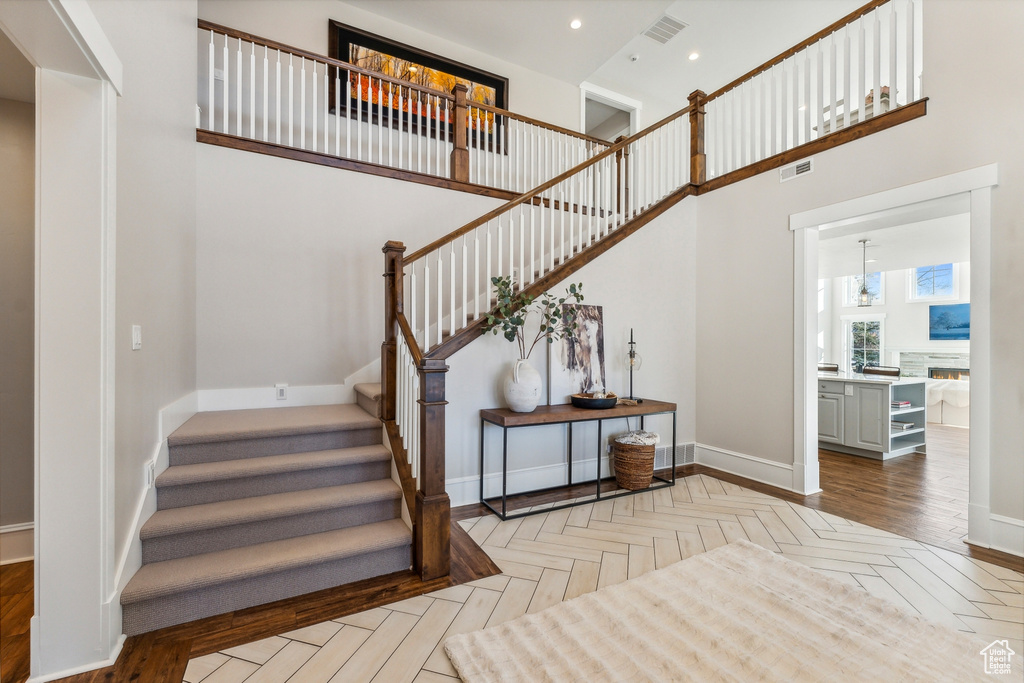 Staircase with parquet flooring and a towering ceiling
