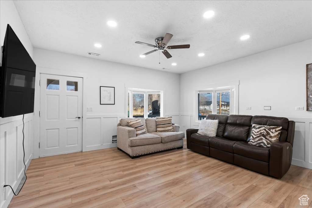 Living room with a textured ceiling, light hardwood / wood-style flooring, and ceiling fan