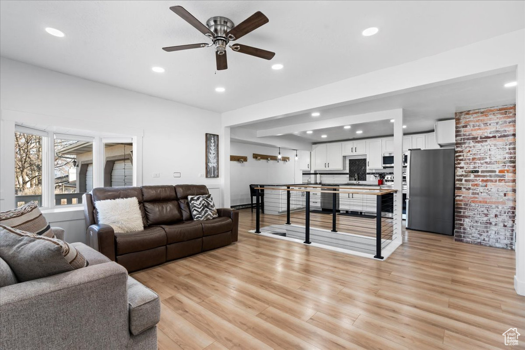 Living room with light wood-type flooring, ceiling fan, and sink