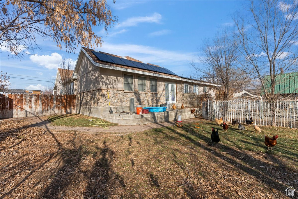 Rear view of property featuring solar panels and a yard