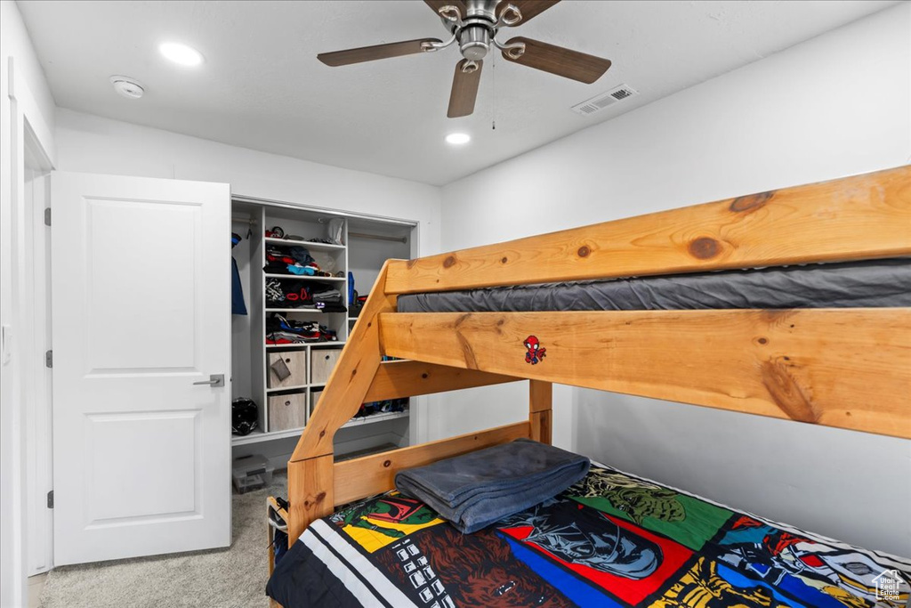 Carpeted bedroom with ceiling fan and a closet