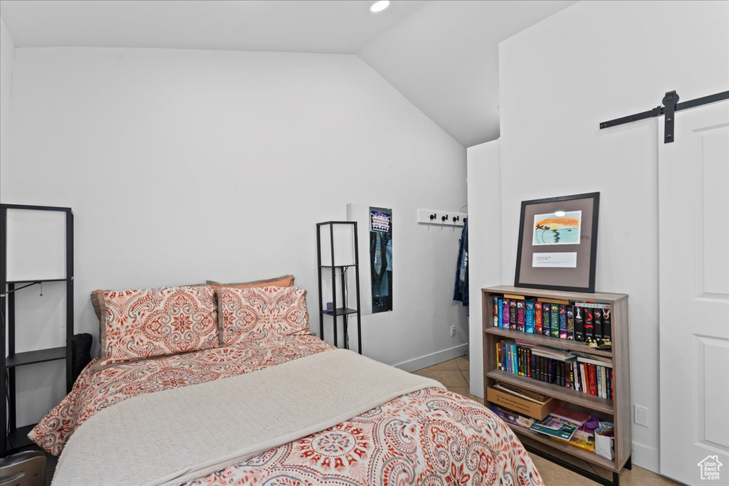 Tiled bedroom featuring a barn door and vaulted ceiling