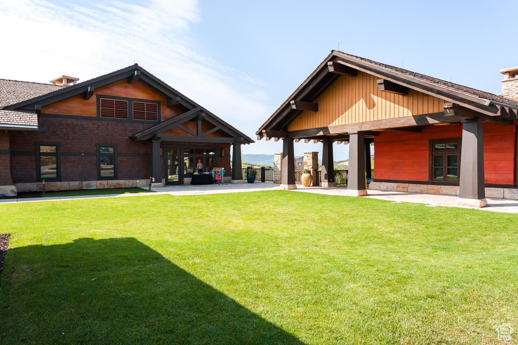 Rear view of property featuring a chimney, a lawn, and a patio area