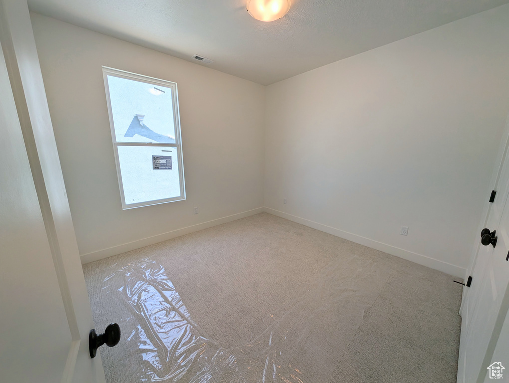 Empty room featuring baseboards, visible vents, and light carpet