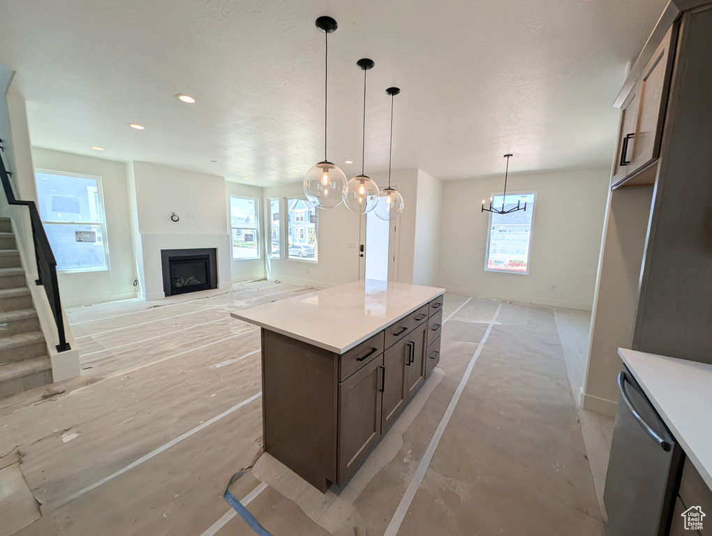 Kitchen featuring a center island, a fireplace, dark brown cabinets, light countertops, and baseboards