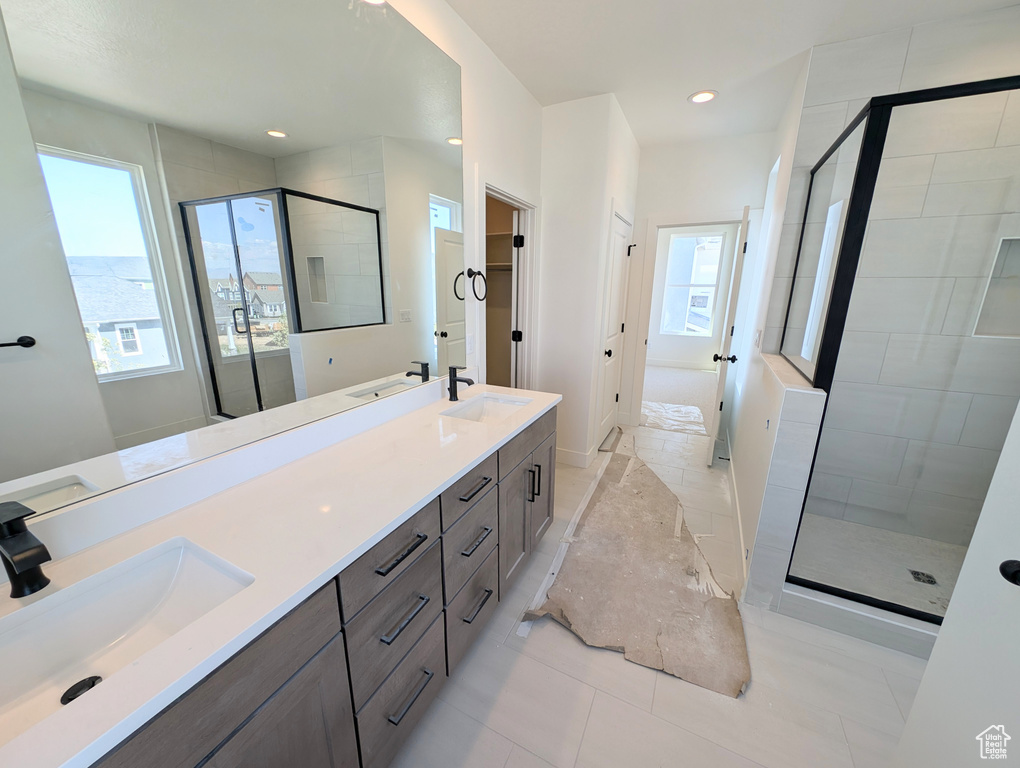 Full bath with double vanity, a sink, and a stall shower