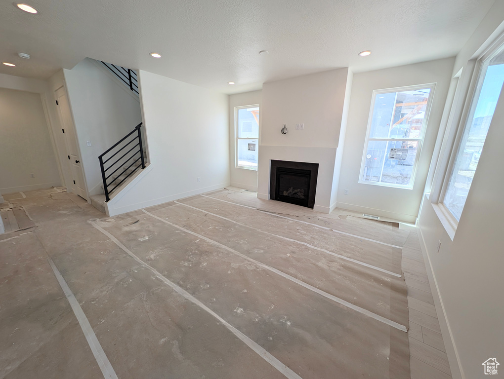 Unfurnished living room with baseboards, a fireplace, a wealth of natural light, and stairway