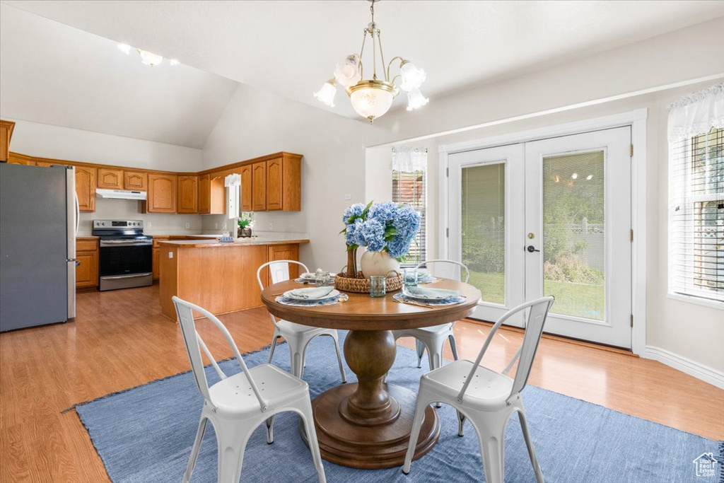 Dining area with light wood finished floors, a chandelier, french doors, and lofted ceiling