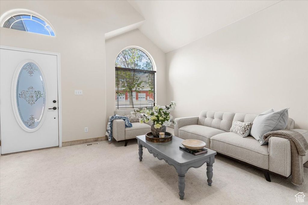 Living area featuring vaulted ceiling, light colored carpet, and baseboards