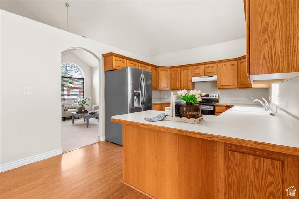 Kitchen with stainless steel appliances, vaulted ceiling, a peninsula, arched walkways, and light countertops