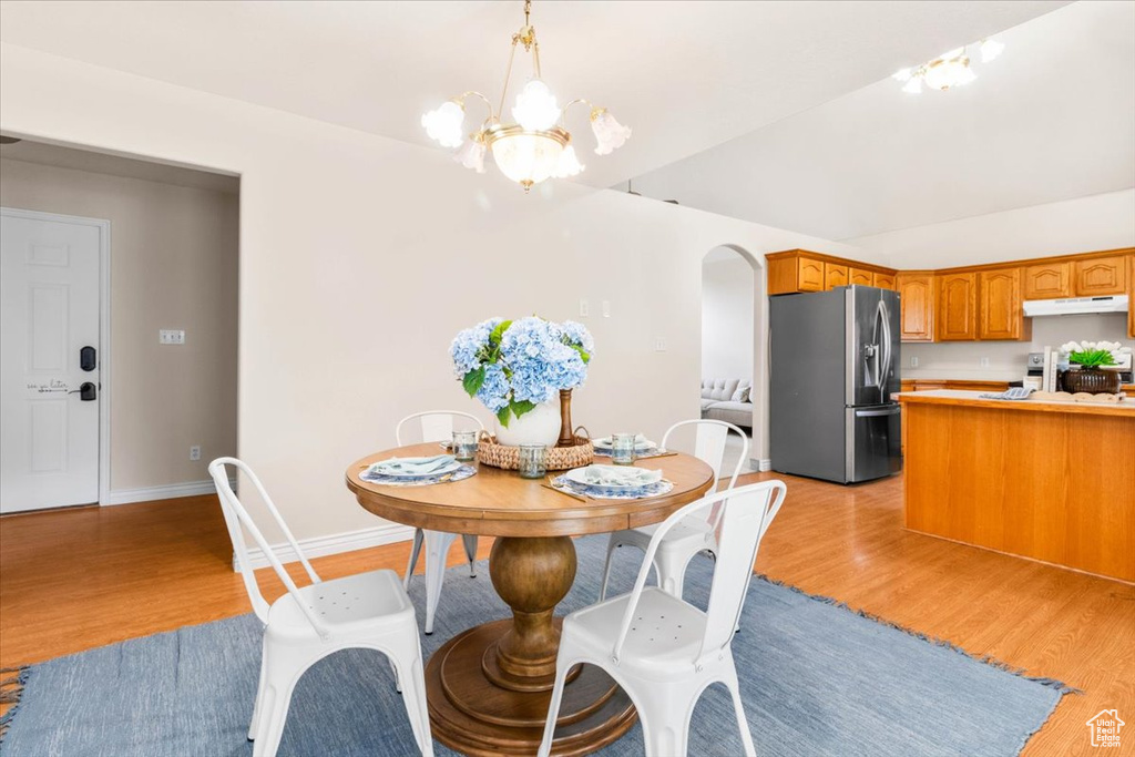 Dining space with light wood-style floors, a chandelier, baseboards, and arched walkways