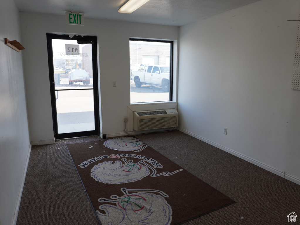 Interior space with an AC wall unit and dark colored carpet