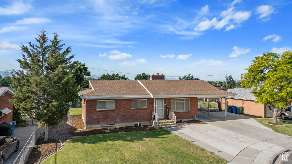 Ranch-style home featuring a carport and a front lawn