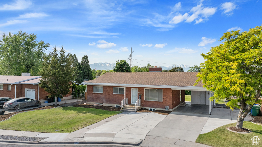 Ranch-style house with a front yard, a mountain view, and a carport