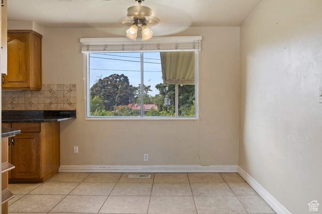 Unfurnished dining area with ceiling fan and light tile patterned floors