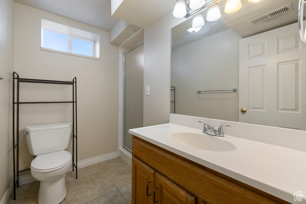 Bathroom featuring tile patterned floors, vanity, toilet, and a shower with shower door