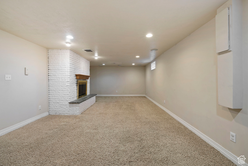 Interior space with carpet flooring, a fireplace, and brick wall